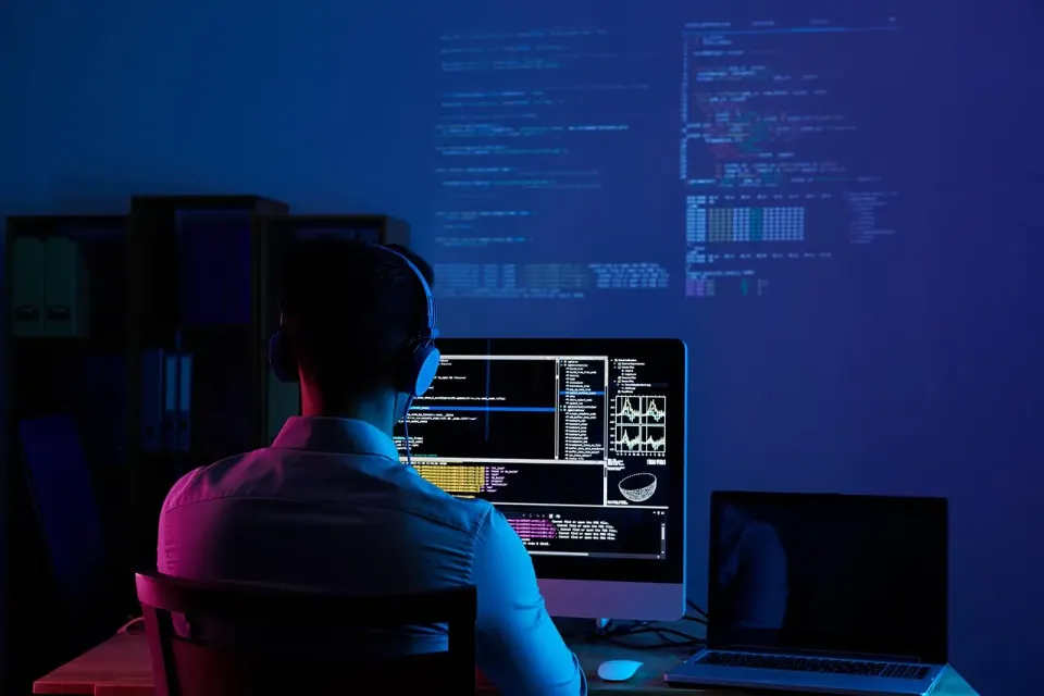 Software developer writing code at a computer with two monitors