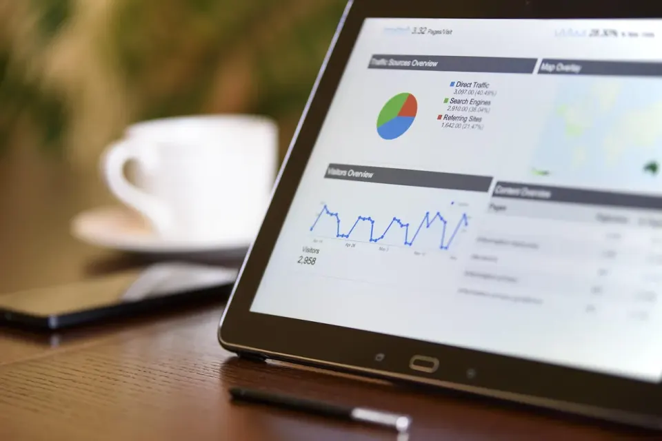 Notebook and laptop on a desk with digital marketing statistics on screen