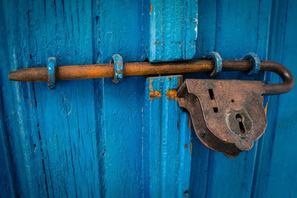 Old lock and latch on a weathered blue wooden door