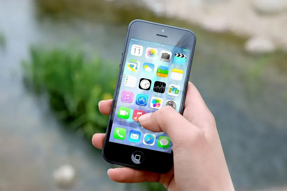 A hand holding a smartphone with apps, where many AI assistant visits begin and referrer data is often lost