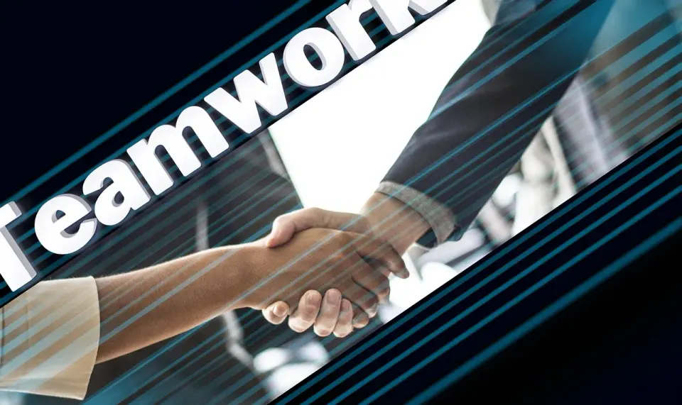 Two business partners shaking hands across a table
